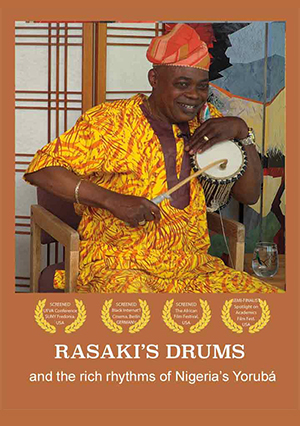 drummer wearing Nigerian clothes with drum; festival laurels below